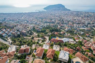 Yorug' Alanya mehmonxonasi, krem rangli charm divanlar, kafel pollari va nafis shift yoritgichlari bilan.