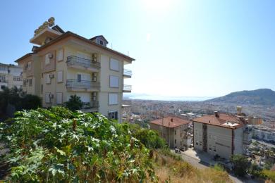Alanya ingatlan erkély csempepadlóval, díszes vas korláttal, és panorámás városi és tengerparti kilátással.