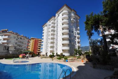 Alanya eiendom balkong med fliser, rekkverk i rustfritt stål og sterkt solskinn med utsikt over byen og havet.