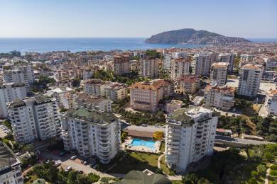 Yorug', ochiq rejadagi Alanya mehmonxonasi zamonaviy oshxonasi, bej mebellari, balkoniga chiqish imkoniyati va iliq, jozibali muhitga ega.