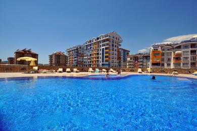 Alanya woning keuken met witte kasten, roestvrijstalen koelkast, tegelvloer en een heldere, luchtige sfeer.