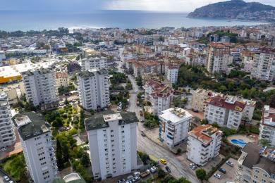Dnevna soba u Alanyi sa otvorenom kuhinjom, smeđim sofama i svijetlom, primamljivom atmosferom.