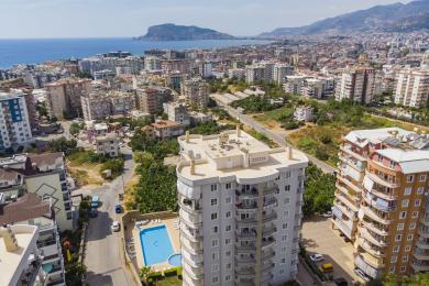 Alanya woning balkon met wicker meubilair, glazen tafel en prachtig uitzicht op de stad en de zee.