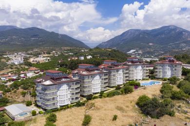 Alanya mulkidagi stol, stullar va shahar, dengiz va basseynning panoramik ko'rinishlari bilan balkon.