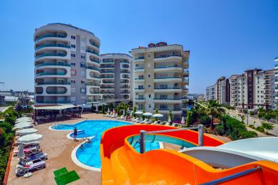 Alanya eiendom balkong med glassrekkverk, flislagt gulv og lyse, solfylte utsikter over byen.