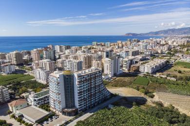 Alanya mulkidagi qizil divan, naqshli stullar va yorqin, jozibali yoritishga ega yashash xonasi.
