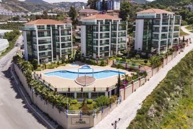 Yorug' Alanya kvartirasining yashash xonasi, kafel pollari, poldan shiftgacha bo'lgan derazalar va manzarali ko'rinishga ega balkon.