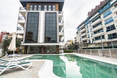 Alanya mulki: Zamonaviy oshxona silliq kulrang shkaflar, yog'och aksanlar, marmar orqa fon va yorug', havodor muhitga ega.