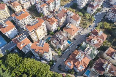 ساختمان آپارتمانی مدرن با بالکن و تراس پشت بام، در یک منظره سرسبز و استوایی واقع شده است.