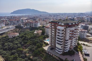 Alanya mulkidagi ko'rinishda "FOKUS" so'zi yozilgan hovuz, atrofida serhosil ko'katlar va shahar manzaralari mavjud.