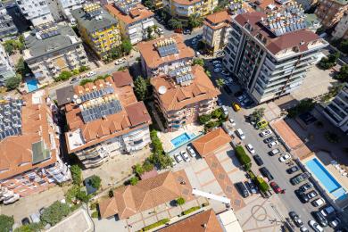 Sunčani balkon u Alanji sa belim stolom i stolicama, koji nudi pogled na grad.