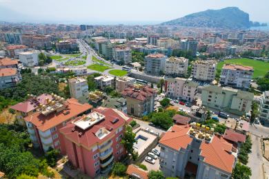 Sunčani balkon apartmana u Alanji s ležaljkom i blagovaonskim setom s prekrasnim pogledom na grad i planine.