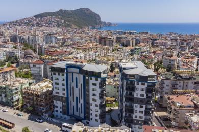 Svijetli balkon u Alanji sa staklenim ogradama nudi zadivljujući pogled na grad i more kroz velika klizna staklena vrata.