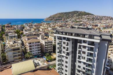 Vardagsrum i en ljus fastighet i Alanya med stora fönster med havsutsikt, marmorgolv och en trappa.
