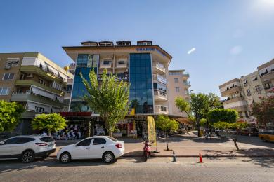اتاق نشیمن ملک آلانیا با مبل بژ، کف کاشی، دسترسی به بالکن و نورپردازی مدرن.