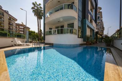 A világos, modern Alanya apartman nyitott konyhával, fényes fehér szekrényekkel és kényelmes nappalival rendelkezik.
