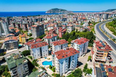 Pogled s balkona apartmana u Alanji koji prikazuje grad, more i planinske vizure, savršen za objedovanje na otvorenom.