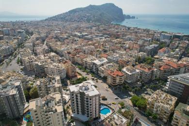Alanya mulki zamonaviy kulrang divan, ovqatlanish joyi va yorqin yoritilgan yashash xonasiga ega bo'lib, qulay muhit yaratadi.