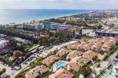 اتاق نشیمن روشن در آلانیا با کف کاشی، مبل‌های مخمل و منظره‌ای از سبزیجات سرسبز.