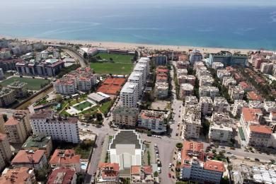 Obývacia izba v Alanyi s moderným dekorom, mramorovou podlahou, zapusteným osvetlením a otvorenou kuchyňou.