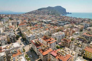 Yorug' Alanya kvartirasining kafel pollari, qulay o'rindiqlari, ovqatlanish joyi va dekorativ deraza san'ati bilan jihozlangan yashash xonasi.