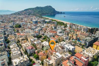Alanya mulkidagi balkon, unda tol mebellar, naqshli kafel pol va soyali ochiq havoda yashash uchun yashil soyabon mavjud.