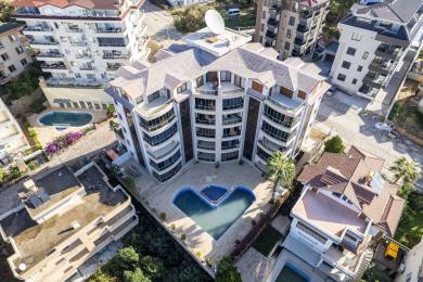 Alanya mulki: Shisha devorlar, tol mebellar va shahar manzaralariga qaragan yorug', havodor muhitga ega yopiq balkon.