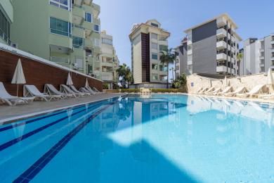 Yorug' Alanya quyosh xonasida katta deraza, basseyn manzarasi, qulay o'rindiqlar va zamonaviy, minimalist dekor mavjud.