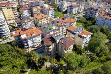 Svijetli dnevni boravak otvorenog plana i blagovaonica u objektu u Alanji imaju podove od pločica, modernu kuhinju i udoban namještaj.