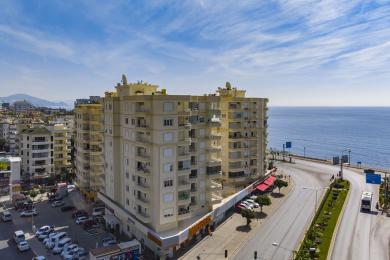 Alanya eiendom balkong med trebord, stoler og fantastisk havutsikt i lyst, naturlig lys.