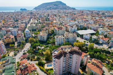 Alanya mulkidagi plitka qoplamali balkon, zanglamaydigan po'latdan yasalgan panjaralar va shaharning yorqin, quyoshli manzarasi.