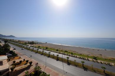 Pogled s balkona nekretnine u Alanji koji prikazuje plažu, Sredozemno more i sunčanu obalnu cestu.