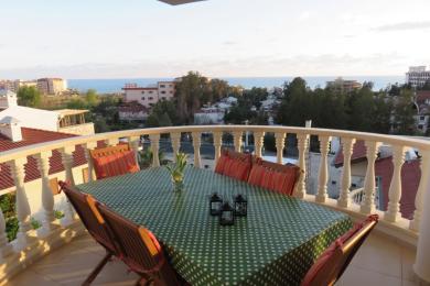 Alanya mulkidagi balkonda ovqatlanish stoli, stullar va dengizning go'zal manzarasi mavjud.