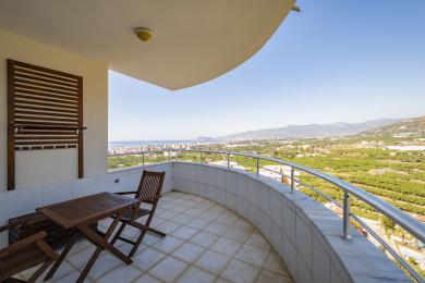 Alanya mulkidagi yog'och mebellar, kafel qoplamasi va shahar va tog'larning ajoyib panoramik manzaralari bilan jihozlangan balkon.