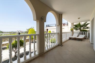 Balkon nekretnine u Alanji sa lučnim otvorima, belim ogradama, podom od pločica i sunčanim pogledom na baštu.
