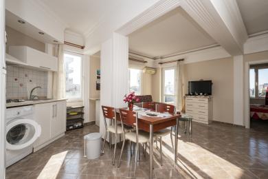 Svijetli apartman u Alanji ima otvorenu kuhinju, blagovaonicu i dnevni boravak s podovima od pločica i prirodnim svjetlom.