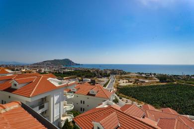 Alanya mulkining ko'rinishi qizil черепица tomlarni, oq binolarni va tiniq moviy osmon ostida ajoyib O'rta er dengizi panoramasini namoyish etadi.