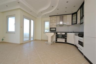 Yorug' Alanya oshxonasi oq shkaflar, plitka orqa fon, nonushta stoli va katta balkon eshiklariga ega bo'lib, havodor muhit yaratadi.
