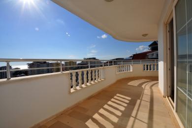 Alanya eiendom balkong med fliser, hvite rekkverk og fantastisk havutsikt under sterkt sollys.