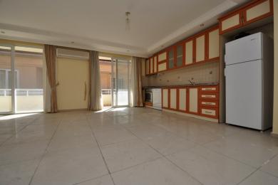Yorqin Alanya oshxonasi kafel pollari, to'q sariq va krem rangli shkaflar va balkon chiqish joyiga ega bo'lib, kenglik hissini yaratadi.