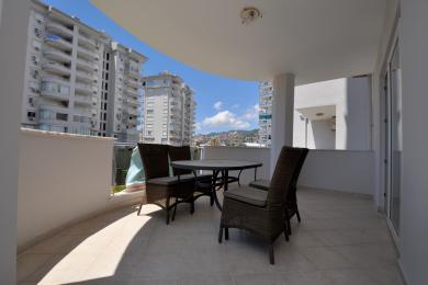 Balkon nekretnine u Alanji sa nameštajem od pruća, podom od pločica i svetlom, prozračnom atmosferom sa pogledom na grad.