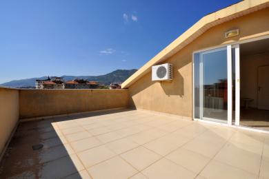 Balkon nekretnine u Alanji sa podnim pločicama, štukaturnim zidovima, kliznim staklenim vratima i pogledom na planine.