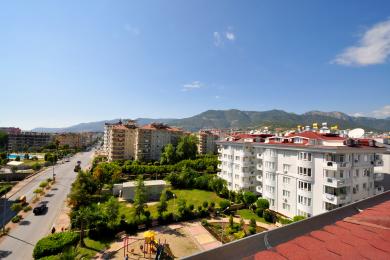 "Alanya mulkining shaharni, tog'larni va tiniq moviy osmonni yuqori nuqtai nazardan namoyish etuvchi ko'rinishi."