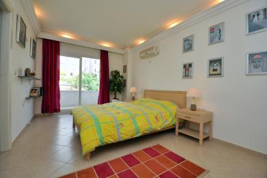 Svetla spavaća soba u Alanji sa pristupom balkonu, sa podovima od pločica, žutim prekrivačem i toplim, prijatnim osvetljenjem.