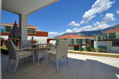Alanya-Immobilienbalkon mit Korbmöbeln, Fliesenboden und hellem, sonnigem Blick auf die Berge.