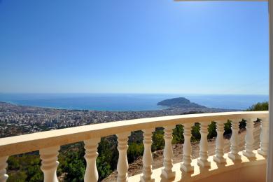 Balkon nekretnine u Alanji sa kamenom balustradom nudi zadivljujući pogled na Sredozemno more i grad pod vedrim plavim nebom.