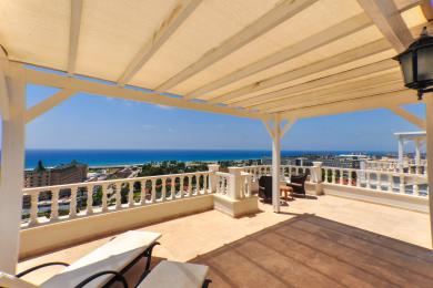 Alānijas īpašuma balkons ar baltu pergolu, akmens grīdu un satriecošiem Vidusjūras skatiem, radot relaksējošu atmosfēru.