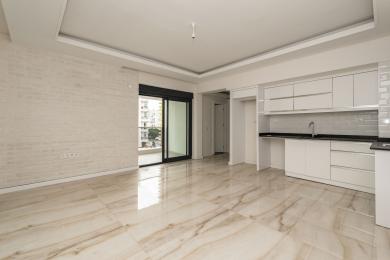 Alanya eiendom: Lyst, moderne stue med marmorgulv, hvit murvegg og elegant kjøkkenområde.
