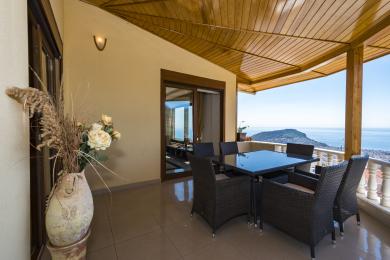 Alanya mulkidagi rattan mebellari, kafel pol, yog'och shift va ajoyib dengiz manzarasi bilan dam olish muhitini yaratuvchi balkon.