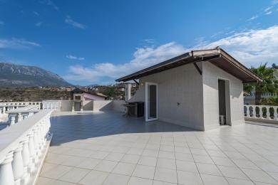 Alanya eiendoms romslige flislagte terrasse har en innebygd grill, og tilbyr lyse, åpne oppholdsrom med fjellutsikt.